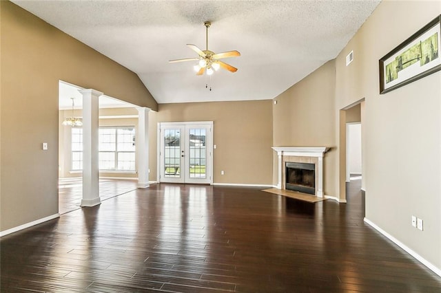 unfurnished living room with visible vents, lofted ceiling, a tile fireplace, wood finished floors, and ornate columns