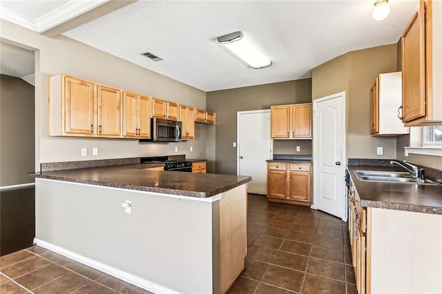 kitchen with black range with gas stovetop, stainless steel microwave, dark countertops, and a peninsula