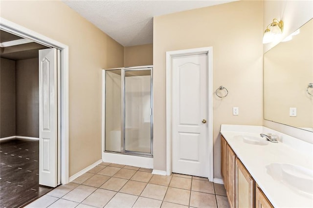 full bath with tile patterned floors, a stall shower, a textured ceiling, and a sink