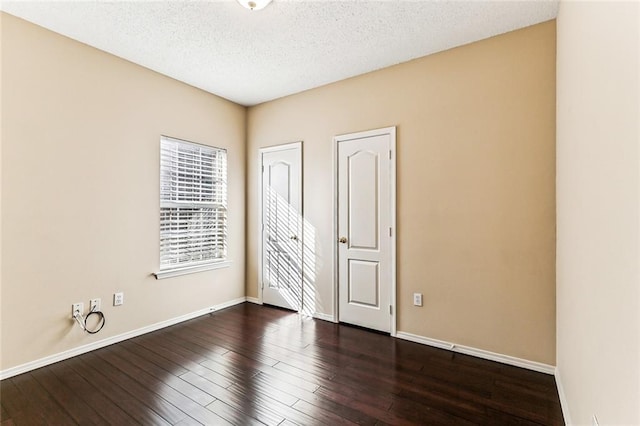 unfurnished room featuring baseboards, a textured ceiling, and dark wood finished floors