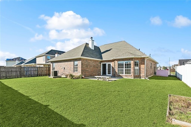 back of house with brick siding, a lawn, and french doors