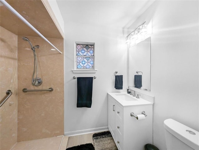 full bathroom featuring baseboards, tiled shower, toilet, and vanity