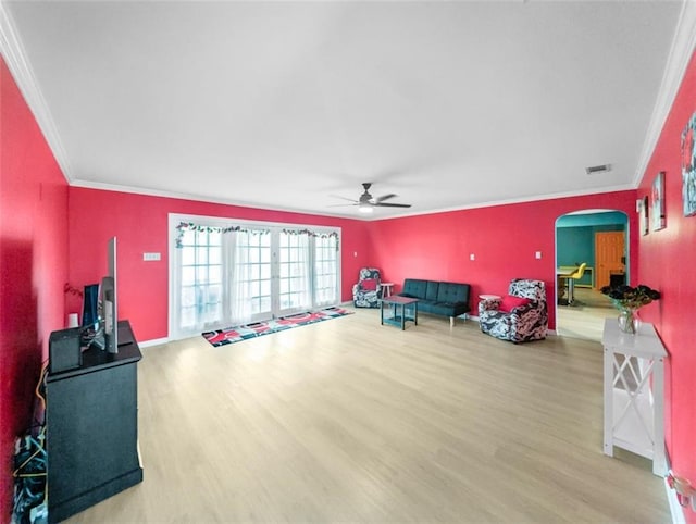 interior space featuring a ceiling fan, visible vents, wood finished floors, arched walkways, and ornamental molding