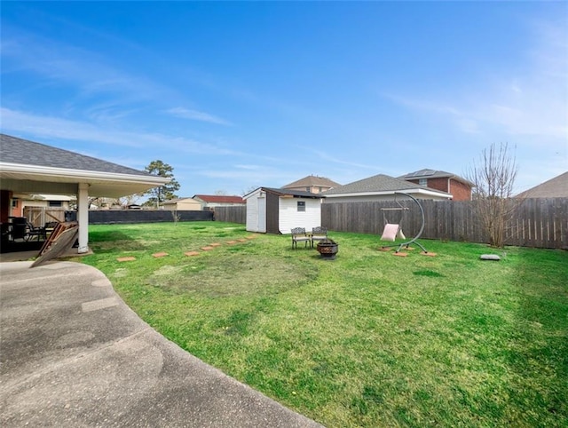 view of yard featuring a shed, an outdoor fire pit, a fenced backyard, an outbuilding, and a patio