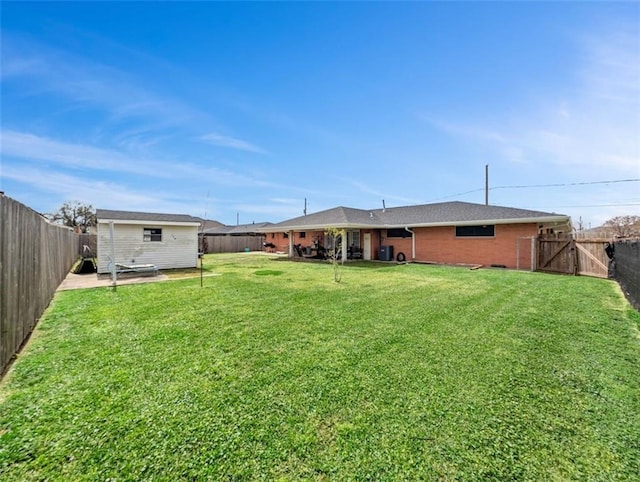 view of yard with an outbuilding, a fenced backyard, and a gate