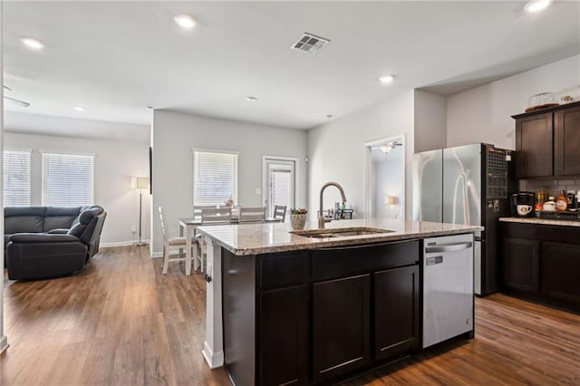 kitchen featuring visible vents, a center island with sink, a sink, dark wood finished floors, and appliances with stainless steel finishes