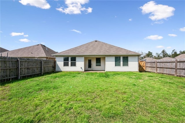 rear view of house with a yard and a fenced backyard