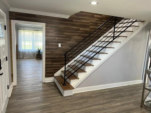 stairway with recessed lighting, wood finished floors, baseboards, and ornamental molding