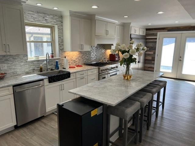 kitchen featuring a healthy amount of sunlight, a kitchen breakfast bar, appliances with stainless steel finishes, french doors, and a sink