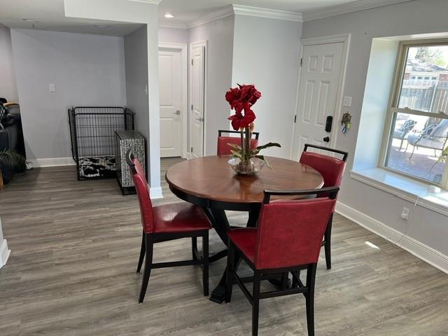 dining room featuring light wood finished floors, baseboards, and ornamental molding