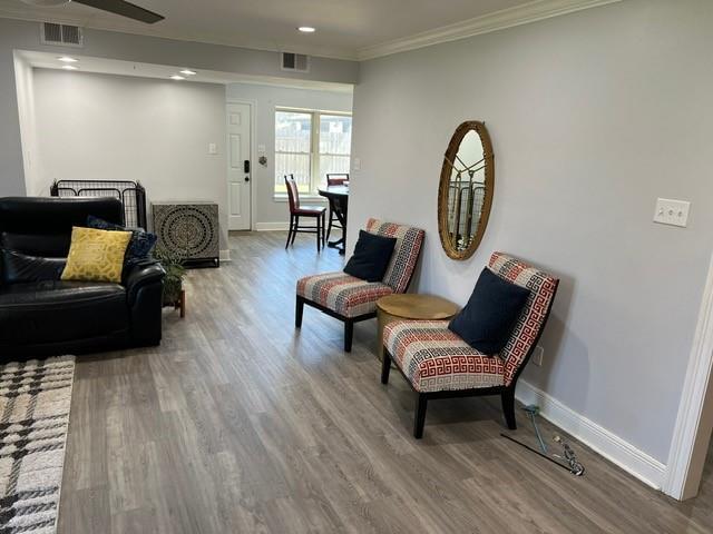 living area featuring wood finished floors, baseboards, and visible vents