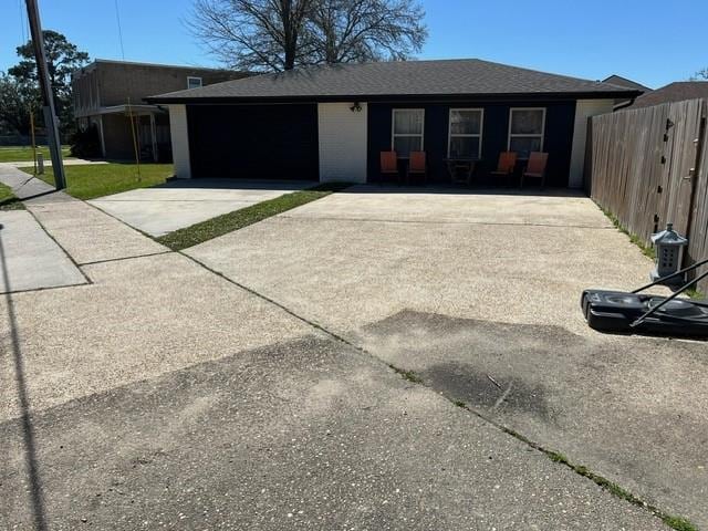 ranch-style house with fence, a garage, driveway, and a shingled roof