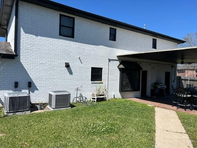 rear view of property featuring central air condition unit, a yard, and brick siding