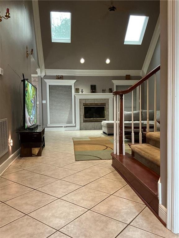 interior space with visible vents, a fireplace, crown molding, light tile patterned floors, and stairs