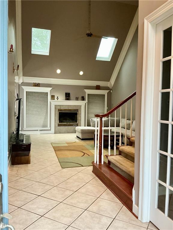 interior space with crown molding, lofted ceiling with skylight, stairway, recessed lighting, and a fireplace