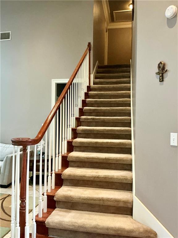 stairs with visible vents, ornamental molding, and wood finished floors