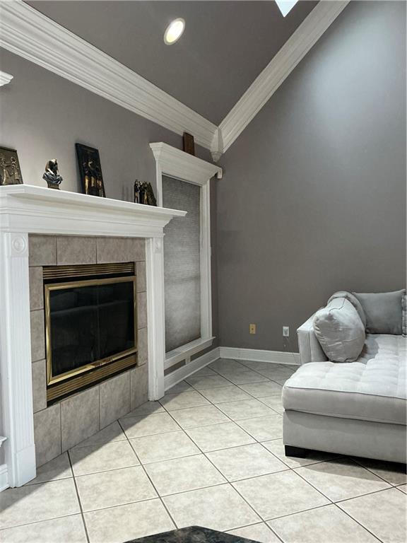 unfurnished living room featuring light tile patterned floors, baseboards, a tiled fireplace, and crown molding