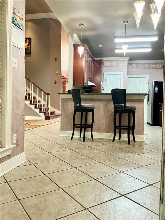 kitchen featuring dark countertops, light tile patterned floors, a breakfast bar area, and freestanding refrigerator