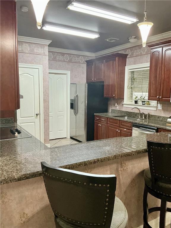 kitchen with a sink, a kitchen breakfast bar, appliances with stainless steel finishes, and ornamental molding