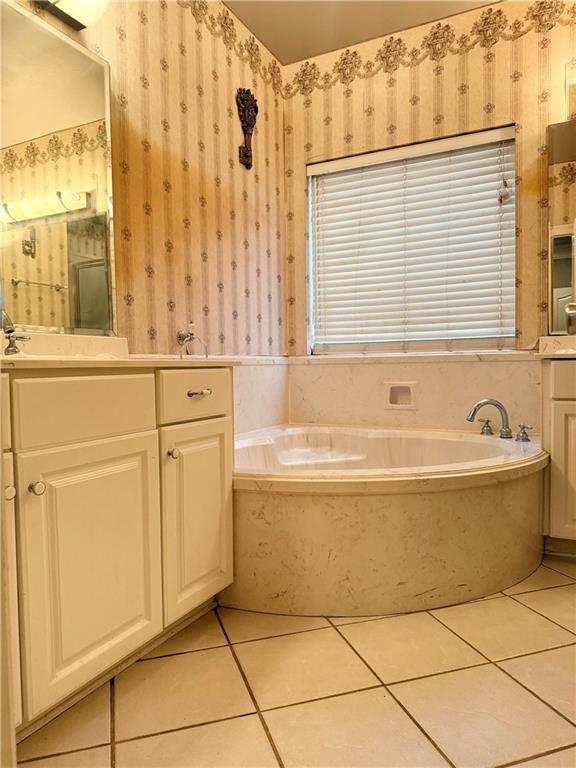 full bath featuring tile patterned flooring, wallpapered walls, vanity, and a garden tub