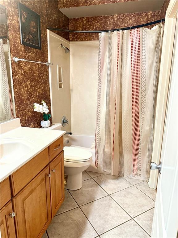 full bathroom featuring tile patterned flooring, shower / bath combination with curtain, vanity, and toilet