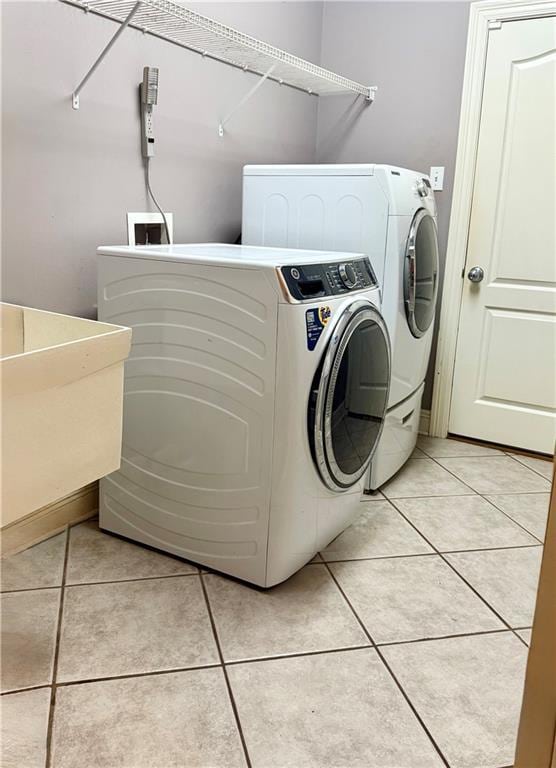 laundry area featuring a sink, light tile patterned flooring, laundry area, and washer and clothes dryer