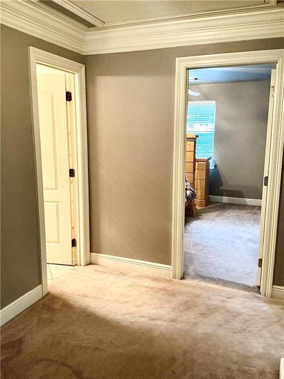 hallway with carpet flooring, crown molding, and baseboards