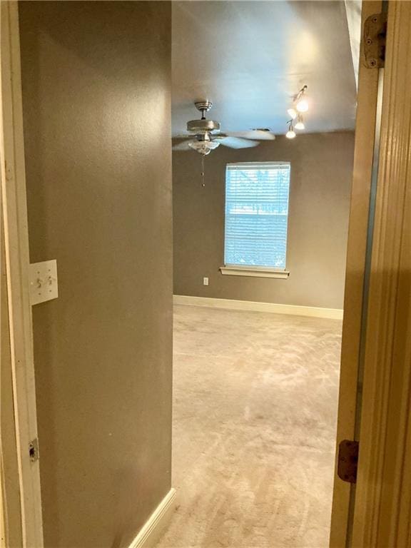 empty room with baseboards, light carpet, and a ceiling fan