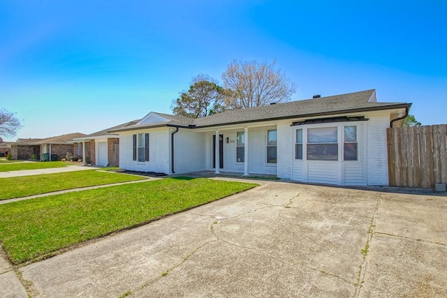 ranch-style home featuring a front lawn, a garage, brick siding, and driveway