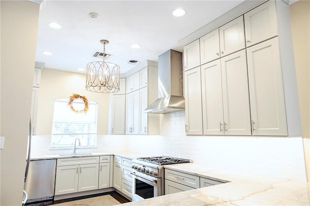 kitchen featuring visible vents, wall chimney range hood, light stone counters, appliances with stainless steel finishes, and a sink