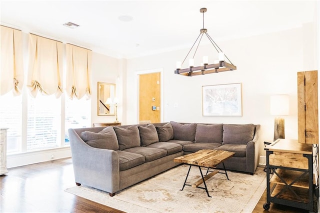 living room with visible vents, baseboards, wood finished floors, and a chandelier