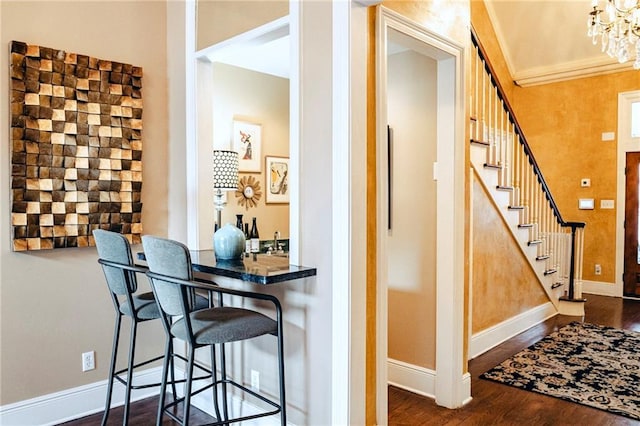 interior space featuring baseboards, dark wood finished floors, an inviting chandelier, stairs, and crown molding