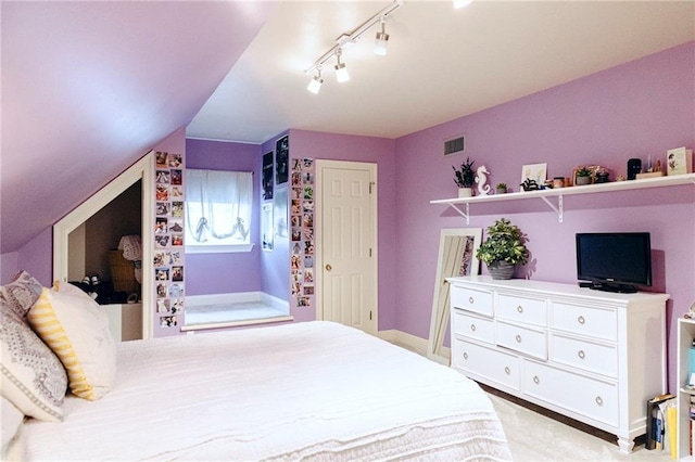 bedroom featuring lofted ceiling, baseboards, visible vents, and track lighting