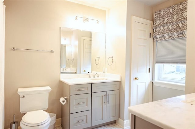 bathroom featuring baseboards, toilet, and vanity