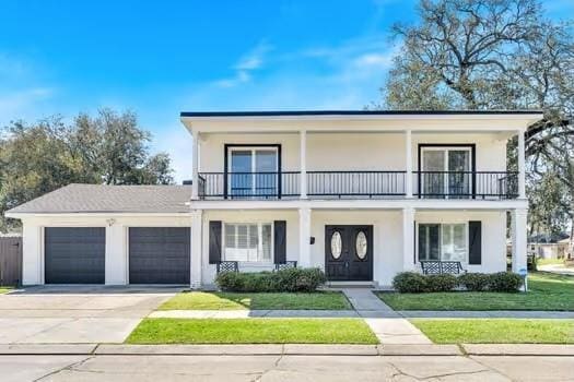 view of front of home featuring stucco siding, an attached garage, and a balcony