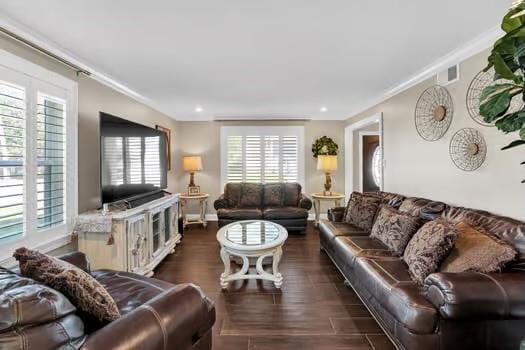 living area with plenty of natural light, dark wood-style flooring, and crown molding