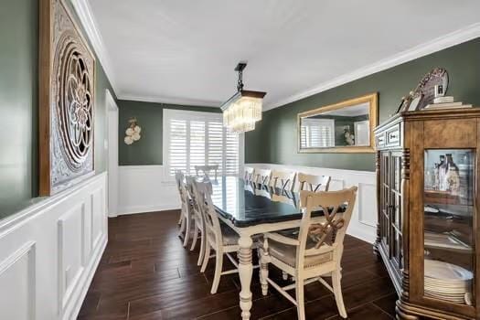 dining area with a chandelier, a wainscoted wall, crown molding, and dark wood-type flooring