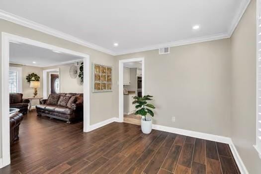 interior space featuring crown molding, wood finished floors, baseboards, and visible vents