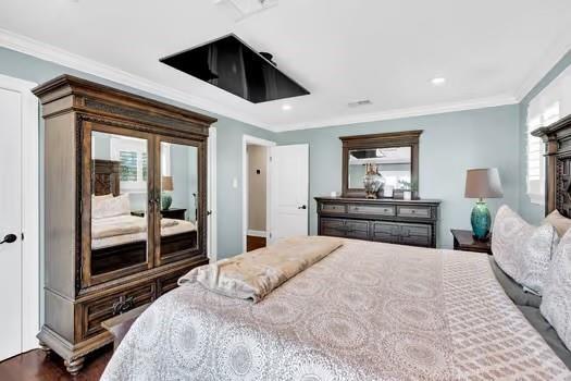 bedroom with crown molding and dark wood-style flooring