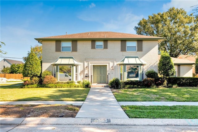 view of front of home with brick siding, a front lawn, and fence