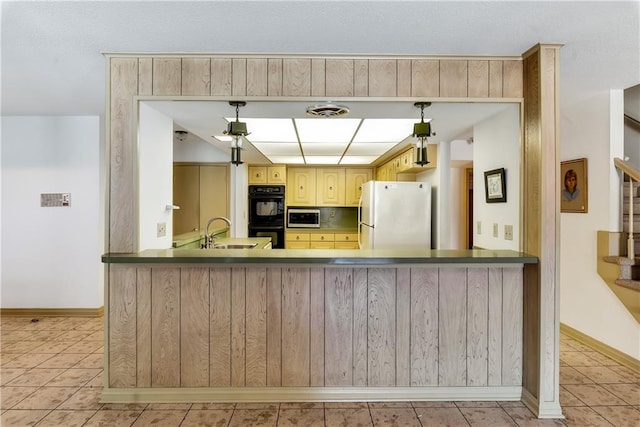 kitchen with stainless steel microwave, light tile patterned floors, freestanding refrigerator, dobule oven black, and a sink