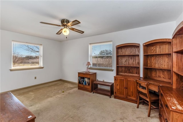 office space with baseboards, light carpet, a healthy amount of sunlight, and ceiling fan