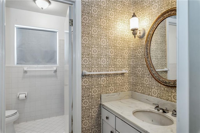 bathroom with toilet, wallpapered walls, and vanity