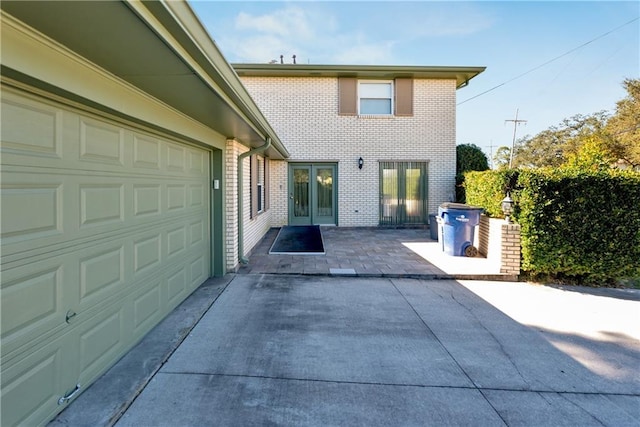 exterior space featuring a garage, a patio, brick siding, and driveway