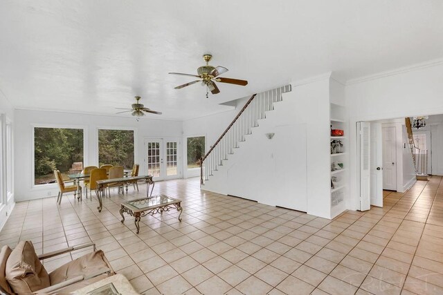 living area with stairway, light tile patterned floors, a ceiling fan, ornamental molding, and french doors