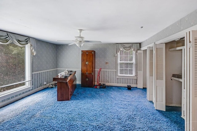 interior space featuring wallpapered walls, carpet flooring, baseboards, and ceiling fan