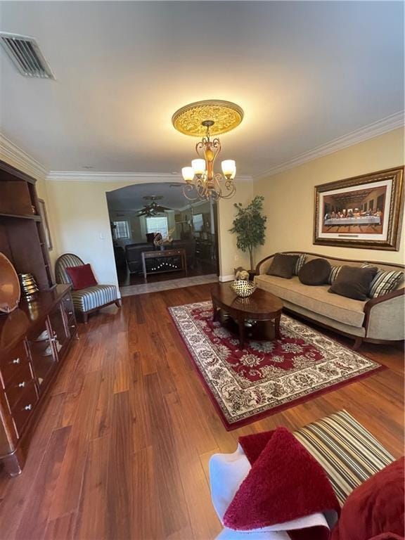 living room featuring visible vents, ornamental molding, ceiling fan with notable chandelier, and wood finished floors