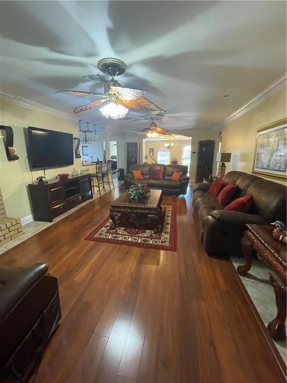 living room with wood finished floors, a ceiling fan, and ornamental molding