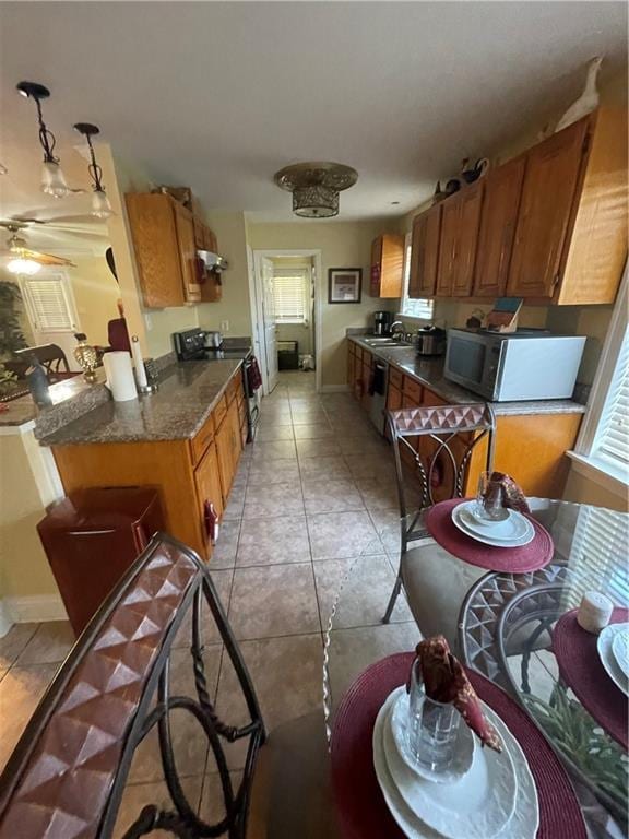 kitchen featuring light tile patterned floors, brown cabinets, dark countertops, and black range with electric cooktop