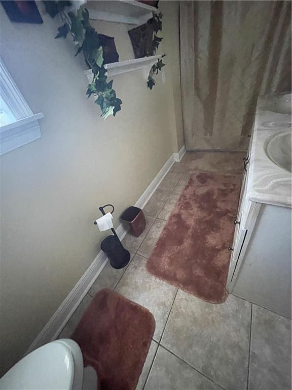 bathroom with tile patterned flooring, toilet, vanity, and baseboards